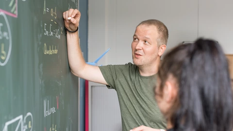 Lehrer erklärt Schülerin Mathematik an der Tafel, individuelle Förderung und Bildung beim CJD.