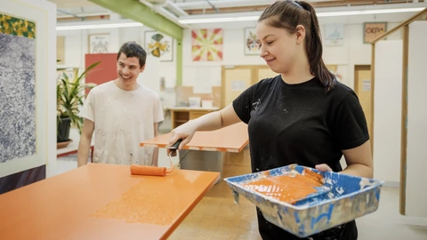 Junger Mann und junge Frau in einer Maler-Werkstatt des CJD