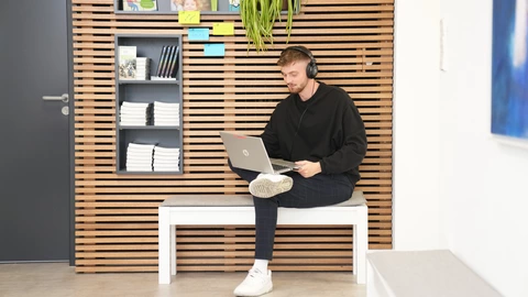 Mitarbeitender des CJD beim Arbeiten am Laptop. Entspannte Atmosphäre.