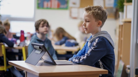 Junge sitzt an einem Schultisch mit Tablet im CJD-Klassenzimmer, digitale Bildung und Lernen in inklusiver Umgebung.