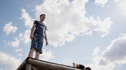 Zwei Junge Männer auf einem Holzpodest vor Himmel und Wolken