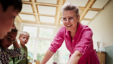 Eine Lehrerin des CJD erklärt drei Grundschülern eine Aufgabe.