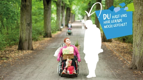  Eine Frau sitzt im Rollstuhl, sie hat Einkaufsbeutel auf Ihrem Schoß und zwischen ihren Beinen. Neben ihr ist eine weiße Lücke in Form eines Menschen. Darüber steht "Du hast uns hier gerade noch gefehlt!"