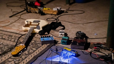 Auf einem Teppich liegen eine E-Gitarre sowie mehrere Effektgeräte, die über Kabel miteinander verbunden sind. Die Szene vermittelt den Eindruck einer Probe oder eines Auftritts, bei dem ein Geburtstagslied vorbereitet oder gespielt wird. Die lose angeordneten Instrumente und Kabel unterstreichen die kreative, spontane Atmosphäre einer musikalischen Darbietung im Rahmen des 75-jährigen CJD-Jubiläums.