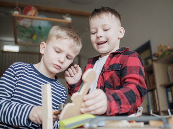 Zwei Kinder spielen mit einem Holzspielzeug
