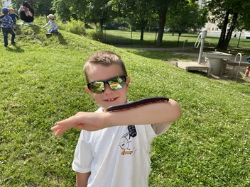 Ein Junge mit einem großen Tausendfüßer auf dem Arm