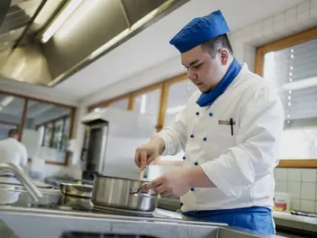 Ein Auszubildender im Bereich Küche bei der Zubereitung eines Gerichts