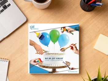 Auf einem Schreibtisch liegt eine Broschüre mit dem Titel "Wie die Zeit vergeht / Chronik – 35 Jahre CJD BBW Gera".