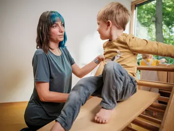 Eine Erzieherin in einer CJD-Kita stützt ein Kind auf einer Rutsche