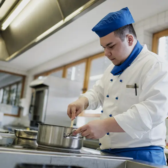 Ein Auszubildender im Bereich Küche bei der Zubereitung eines Gerichts