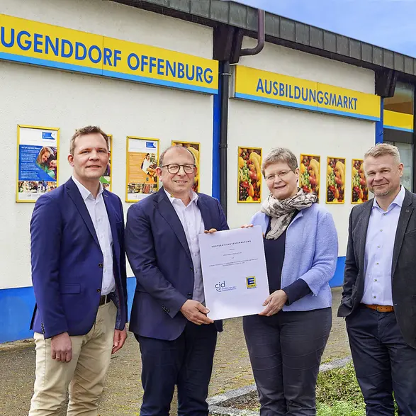 Vier Personen von EDEKA Südwest und CJD vor dem Ausbildungsmarkt bei der Unterzeichnung der Kooperationsvereinbarung.