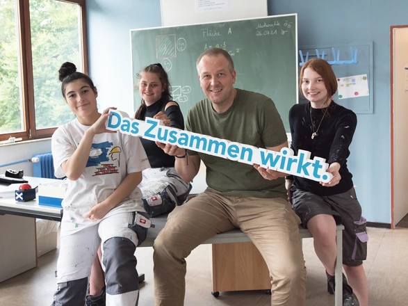 Gruppe von jungen Auszubildenden mit einem Lehrer in einem Klassenzimmer einer Berufsschule des CJD