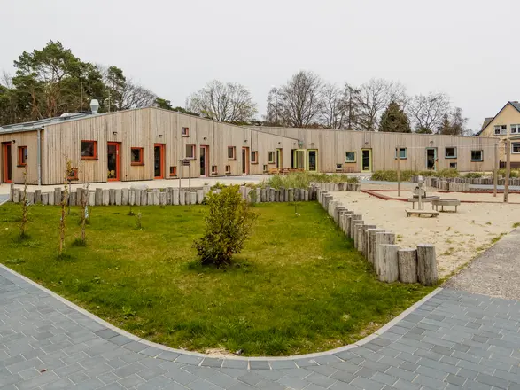 Bild eines Gebäudes aus Holz und eines Spielplatzes