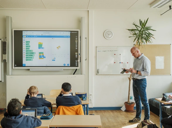 Bild aus einem Klassenzimmer, der Lehrer unterrichtet, die Schüler hören zu