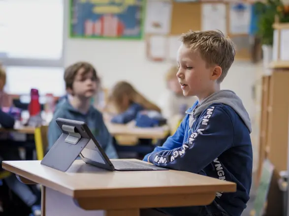 Bild aus einem Klassenraum, ein Schüler schaut in sein Tablet