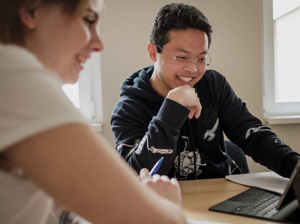 Zwei fröhliche, junge Menschen schauen auf einen Laptop