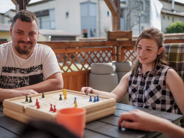 Ein junger Mann spielt Mensch-ärgere-dich-nicht, ein Brettspiel, mit einem jugendlichen Mädchen.