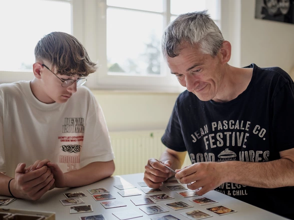 Ein junger Mann spielt Memory, ein Kartenspielt, zusammen mit einem Mann mit Behinderung.