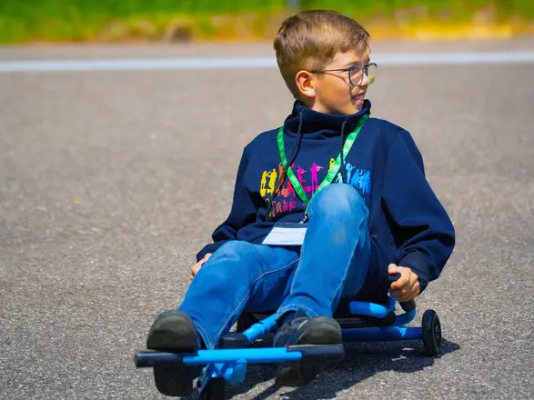 Ein Junge sitzt auf einem einfachen Kart.