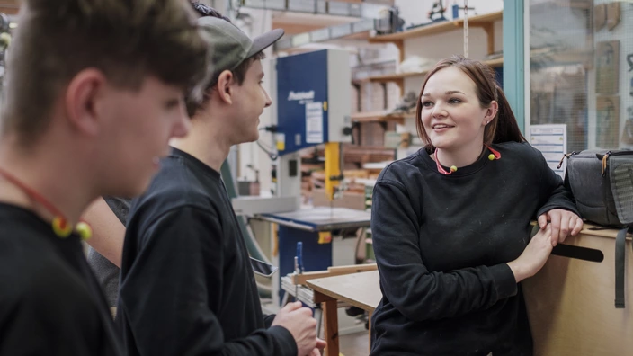 Drei Jugendliche stehen in einer Werkstatt zusammen und unterhalten sich. Spenden helfen jungen Menschen in unseren Berufsbildungswerken ihre Zukunft zu gestalten.