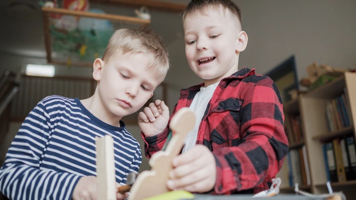 Zwei Kinder spielen mit einem Holzspielzeug