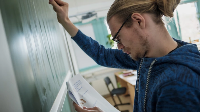 Junger Mann an der Tafel in einem Klassenzimmer einer CJD Schule