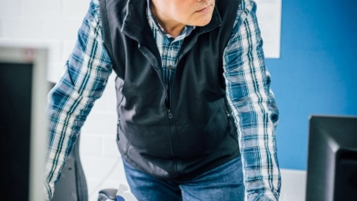 Ausbilder lehnt sich auf seinen Tisch und blickt zur Klasse