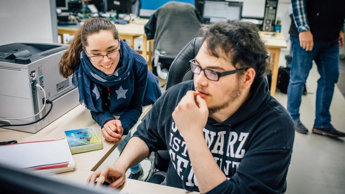 Zwei Auszubildende im Bereich Fachinformatik haben Spaß bei der Arbeit im Büro