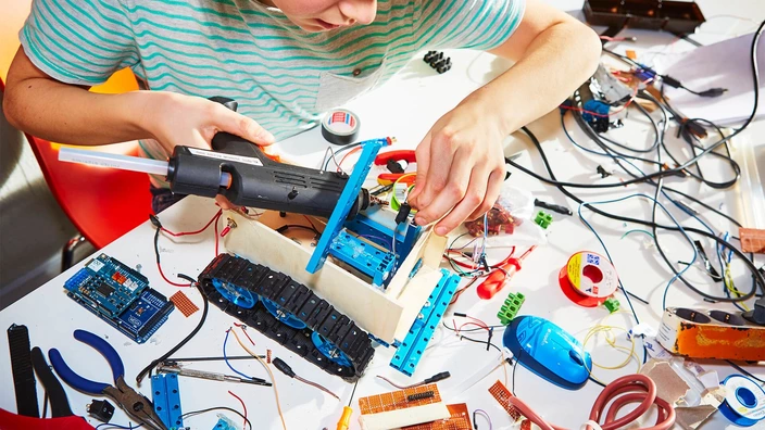 Ein Jugendlicher lötet konzentriert an einem Roboter