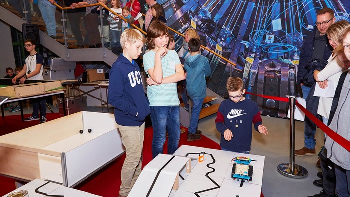 Drei Jugendliche auf einem Roboter-Turnier