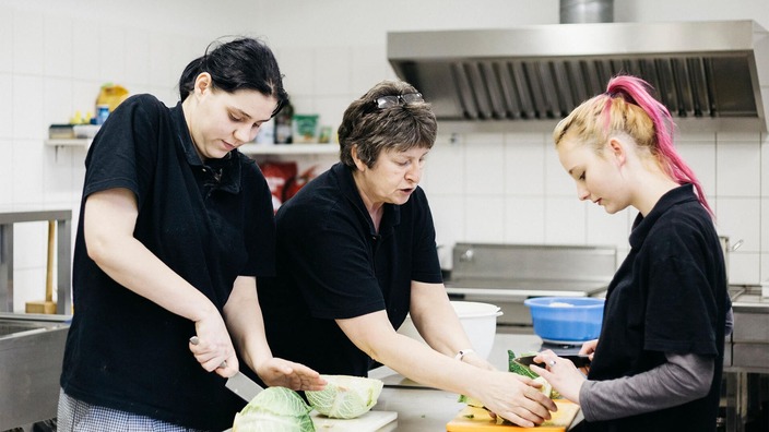 Drei Frauen bereiten Essen in einer Küche vor