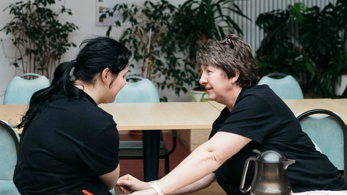 Zwei Frauen unterhalten sich an einem Tisch