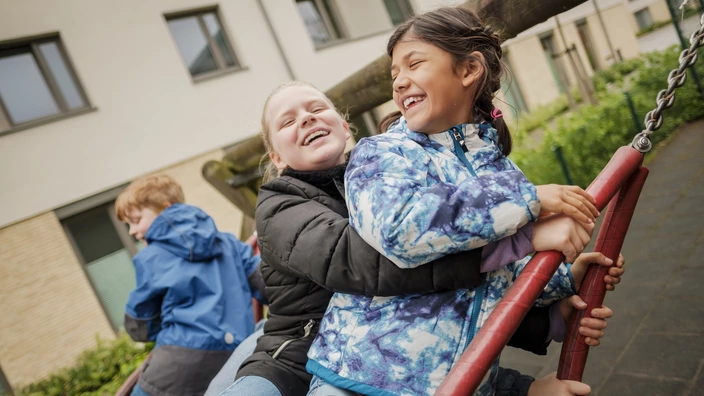  Drei Kinder schaukeln gemeinsam in einer Nestschaukel und lachen dabei. Spenden schenken Kindern Orte der Geborgenheit und Freude.