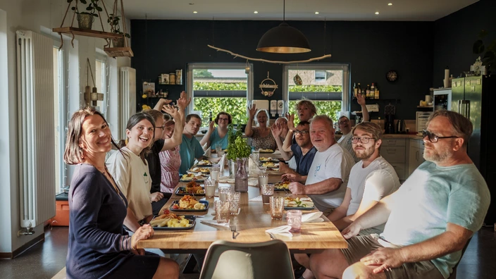 Bewohnerinnen und Bewohner sowie Mitarbeitende sitzen gemeinsam beim Essen