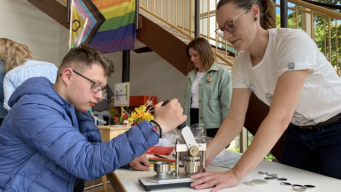 Zwei Menschen an einer Buttonmaschine