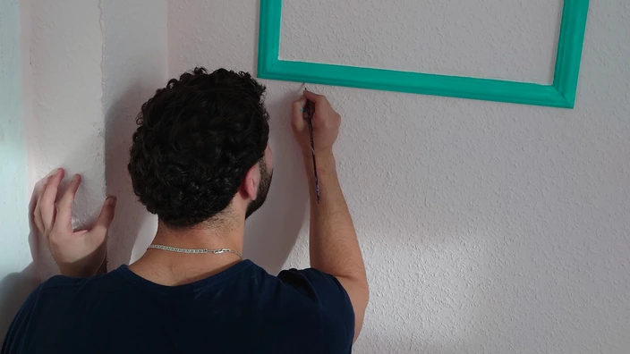 Ein Auszubildender malt einen Rahmen