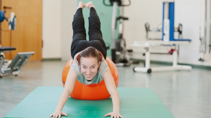 Eine Jugendliche turnt auf einem Gymnastikball.