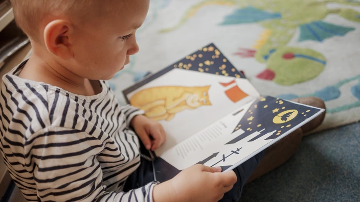 Ein kleiner Junge schaut sich in einer CJD Kita ein Buch an.