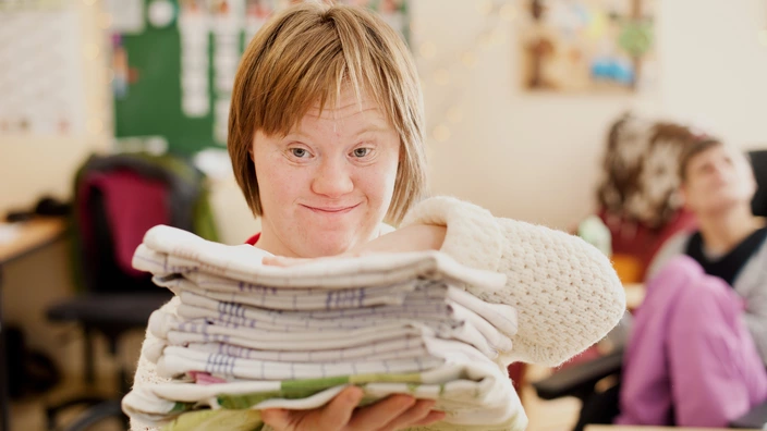 Eine Frau mit einem Stapel Handtücher im Förderzentrum.