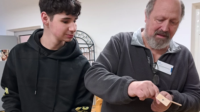 Ausbilder Schreiner zeigt Auszubildenden Holzspielzeug