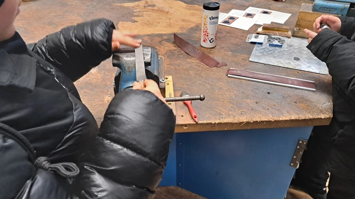 chülerinnen und Schüler probieren in der Metallwerkstatt Feilen und Schleifen von Metall aus