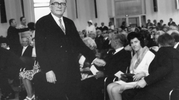 Schwarz-weiß-Foto einer Feier in der Frankfurter Paulskirche 1972 zum 25-jährigen Bestehen des CJD. Ein älterer Mann im Anzug mit Brille geht durch den Mittelgang, während zahlreiche Gäste in festlicher Kleidung auf Stühlen sitzen. Die große Halle mit hohen Fenstern ist gut gefüllt, die Stimmung wirkt feierlich und konzentriert.