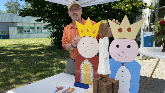 Eine Person steht hinter Würdekönigen aus Holz