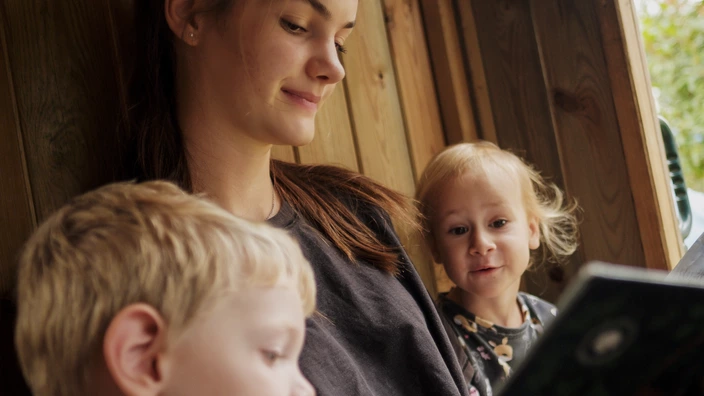 Erzieherin liest zwei Kindern ein Buch vor