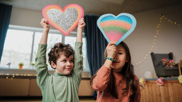 Zwei Kinder halten selbstgebastelte Herzen über ihre Köpfe. Eine Testamentsspende schenkt Kindern in Einrichtungen des CJD Geborgenheit.