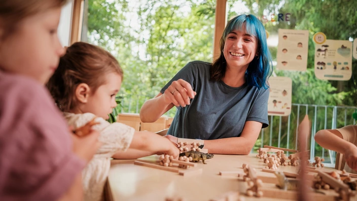 Eine CJD Erzieherin spielt ein Holz-Spiel zusammen mit zwei Mädchen in einer CJD Kita.
