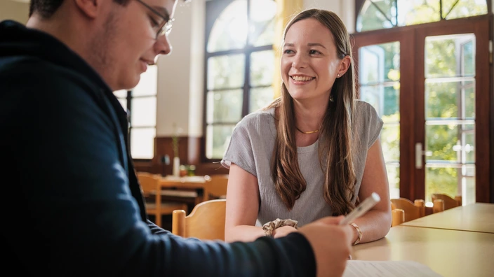 Eine CJD Erzieherin hilft einem Jugendlichen ein Formular auszufüllen.