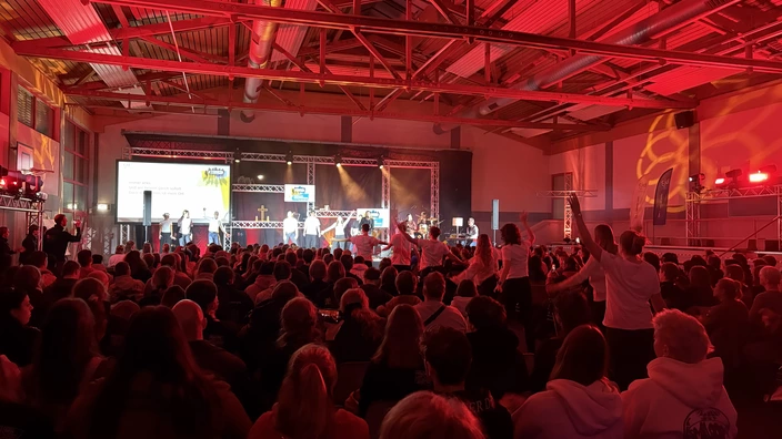 Bild einer Veranstaltung vom Jugendforum in Gera. Die Teilnehmer singen und tanzen zusammen und haben Spaß.