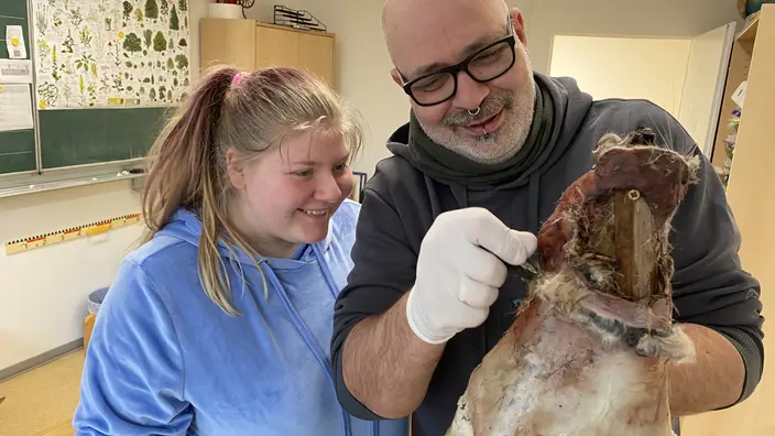 Eine Schülerin und ein Pädagoge beim Gerben eines Kaninchenfelles.