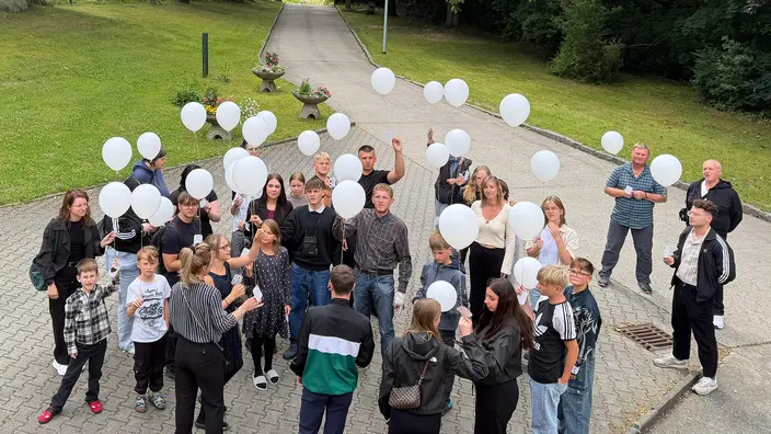 Menschengruppe mit weißen Luftballons